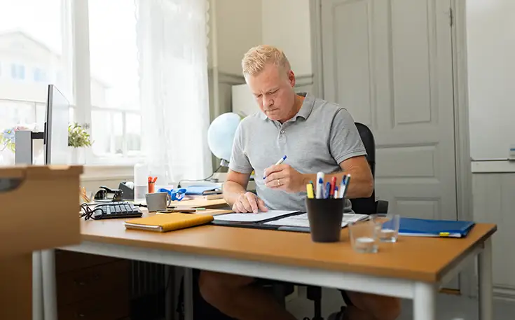 Idrottsläraren sitter vid sitt skrivbord och för anteckningar. 