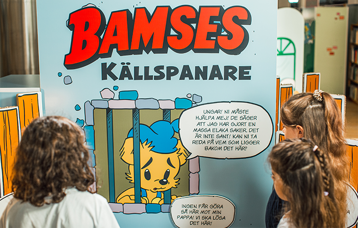 Tre barn utforskar utställningen, där Bamse via en pratbubbla berättar att han blivit felaktigt anklagad och sitter i fängelse.