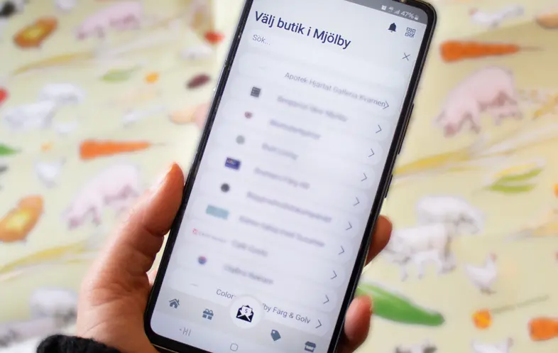 Telefonapp med texten "Välj butik i Mjölby" och en lista med butiker i kommunen.