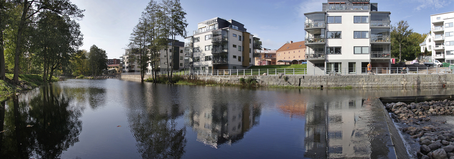 Vita flerbostadshus invid Svartån i Mjölby fotograferade en solig dag. 