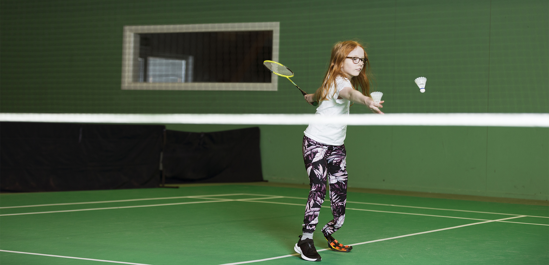 Flicka med fotprotes spelar badminton  