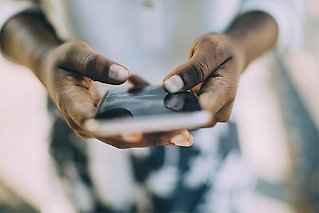 Händer som håller i en mobiltelefon.