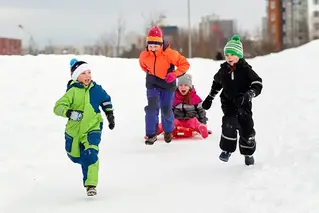 Fyra glada barn som springer i snön.