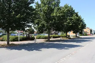 Parkering med bilar, träd, cykelväg och bilväg